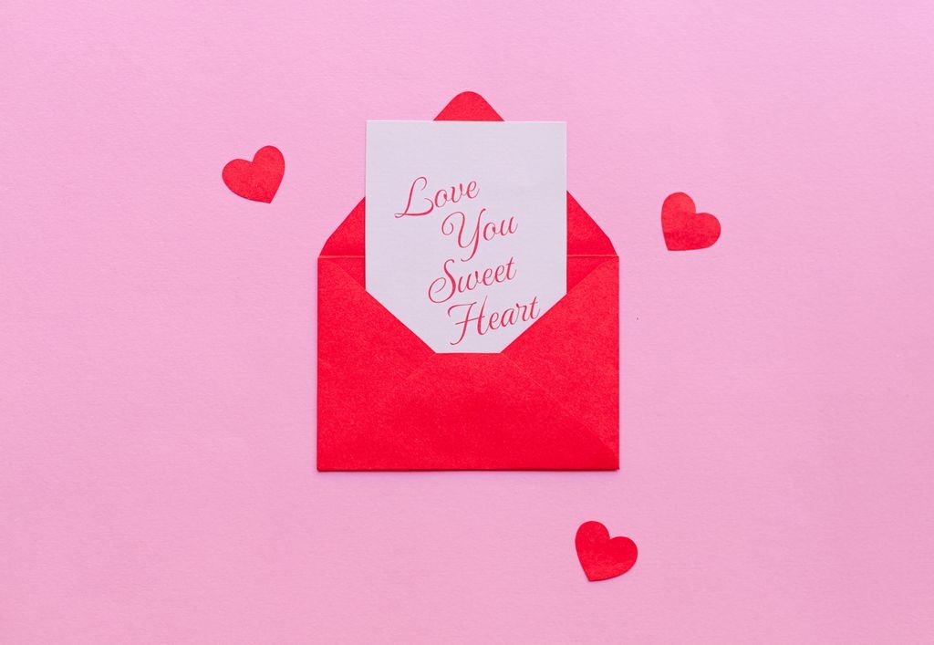A red envelope with a love letter on pink background, ideal for Valentine's.